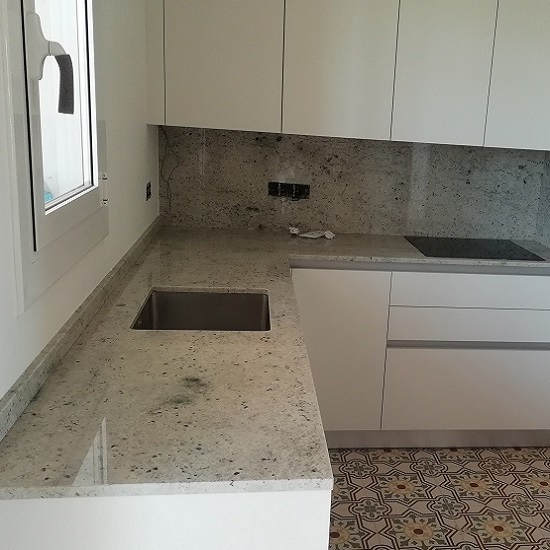 una cocina con encimeras de Granito Colonial White y paredes haciendo juego