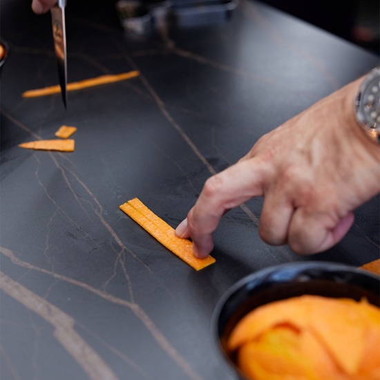 mano cortando naranjas sobre la encimera de porcelánico techlam st laurent
